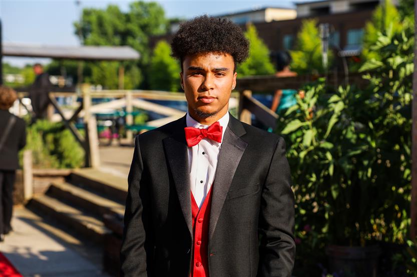 A young men in a tuxedo stands on the red carpet